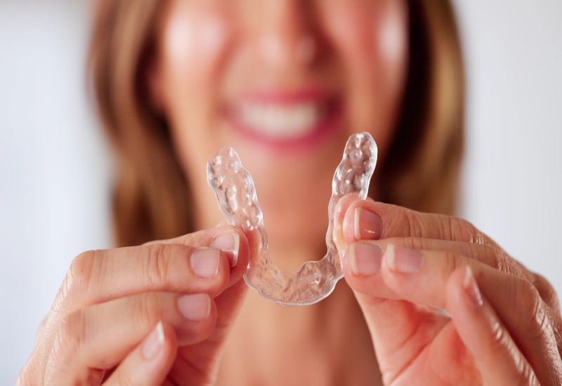 Woman holding Invisalign Clear Aligners in Mokena and New Lenox, IL for discreet orthodontic care